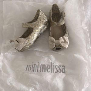 Size 6 Mini Melissa toddler shoes on gold with tan bow